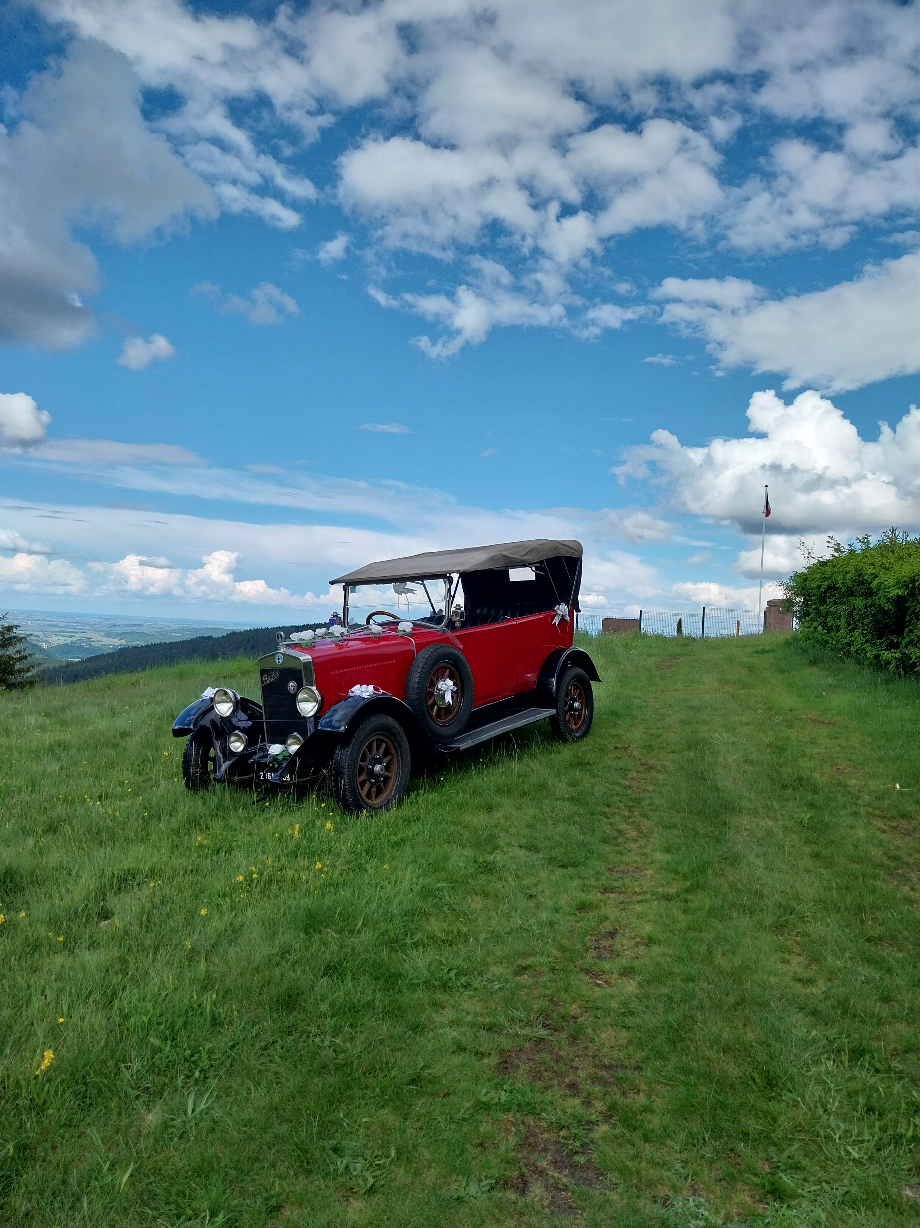 Voiture ancienne décapotable de 1927 rouge bordeau, garé sur un pré.